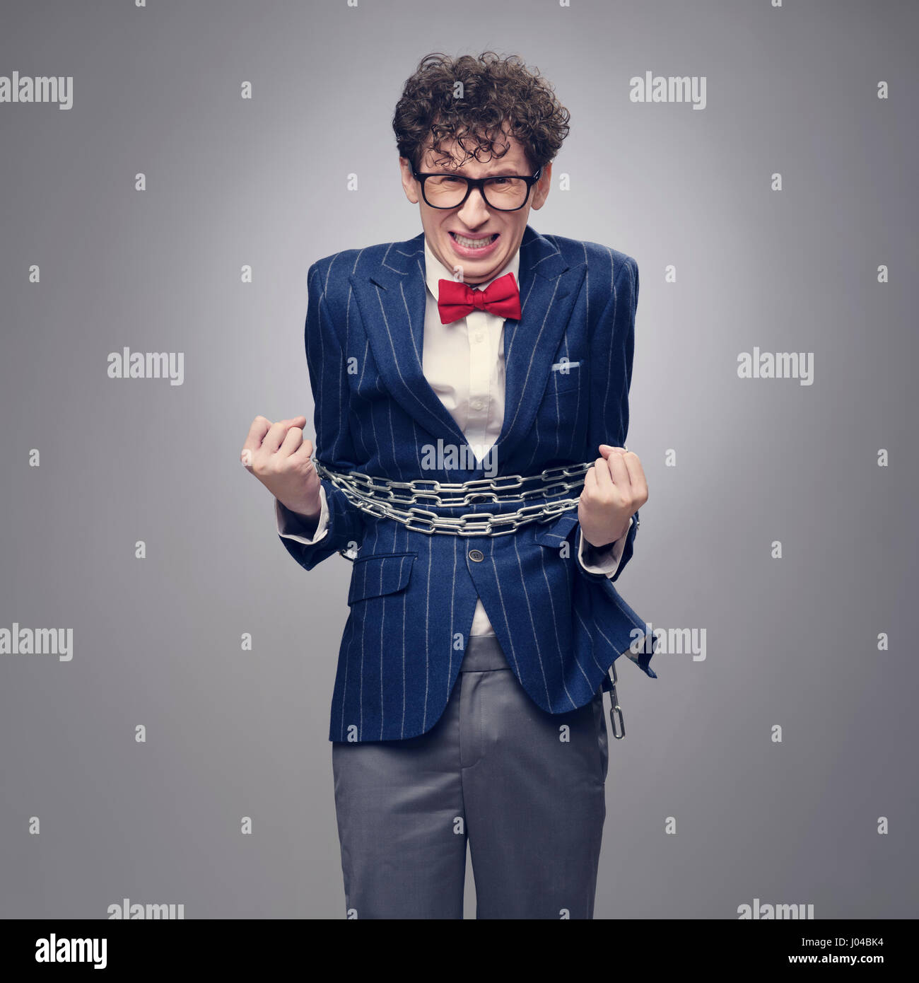 Chained funny business man trying to free himself Stock Photo