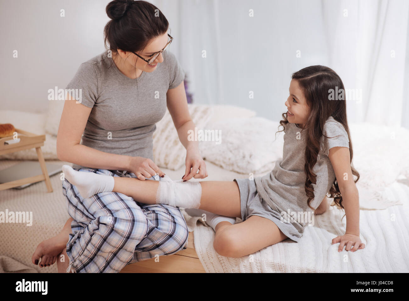 Positive young mother providing treatment to her kid at home Stock Photo