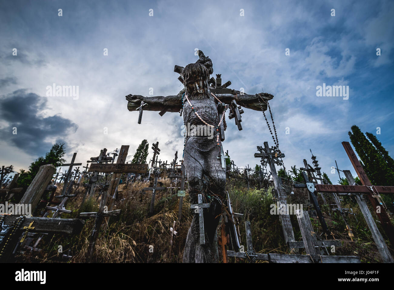 Wooden cross with Jesus sculpture on Hill of Crosses in Lithuania Stock Photo