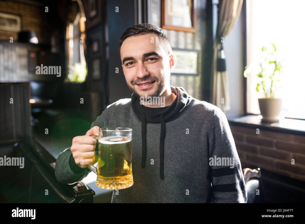 single man in a pub or bar holding the beer high in the air Stock Photo