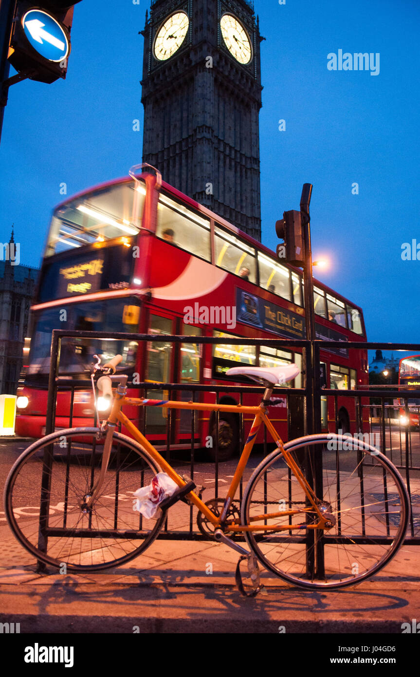 London, England - June 15, 2011: A bicycle is chained in Parliament Square outside the UK Houses of Parliament as a morning bus passes the iconic Big  Stock Photo