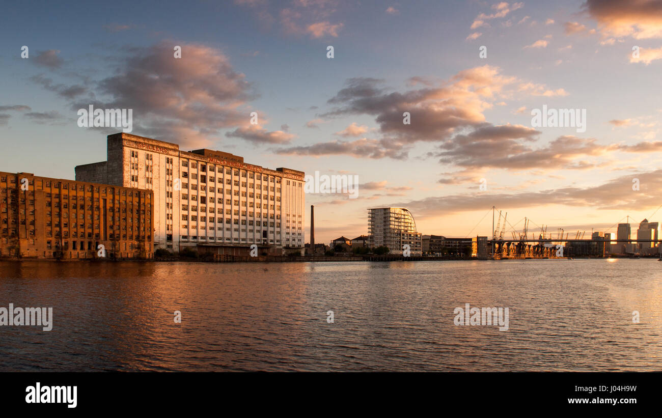 Evening light illuminates the neglected facade of the derelict Millennium Mills building on the Royal Victoria Dock in Newham, east London. Stock Photo