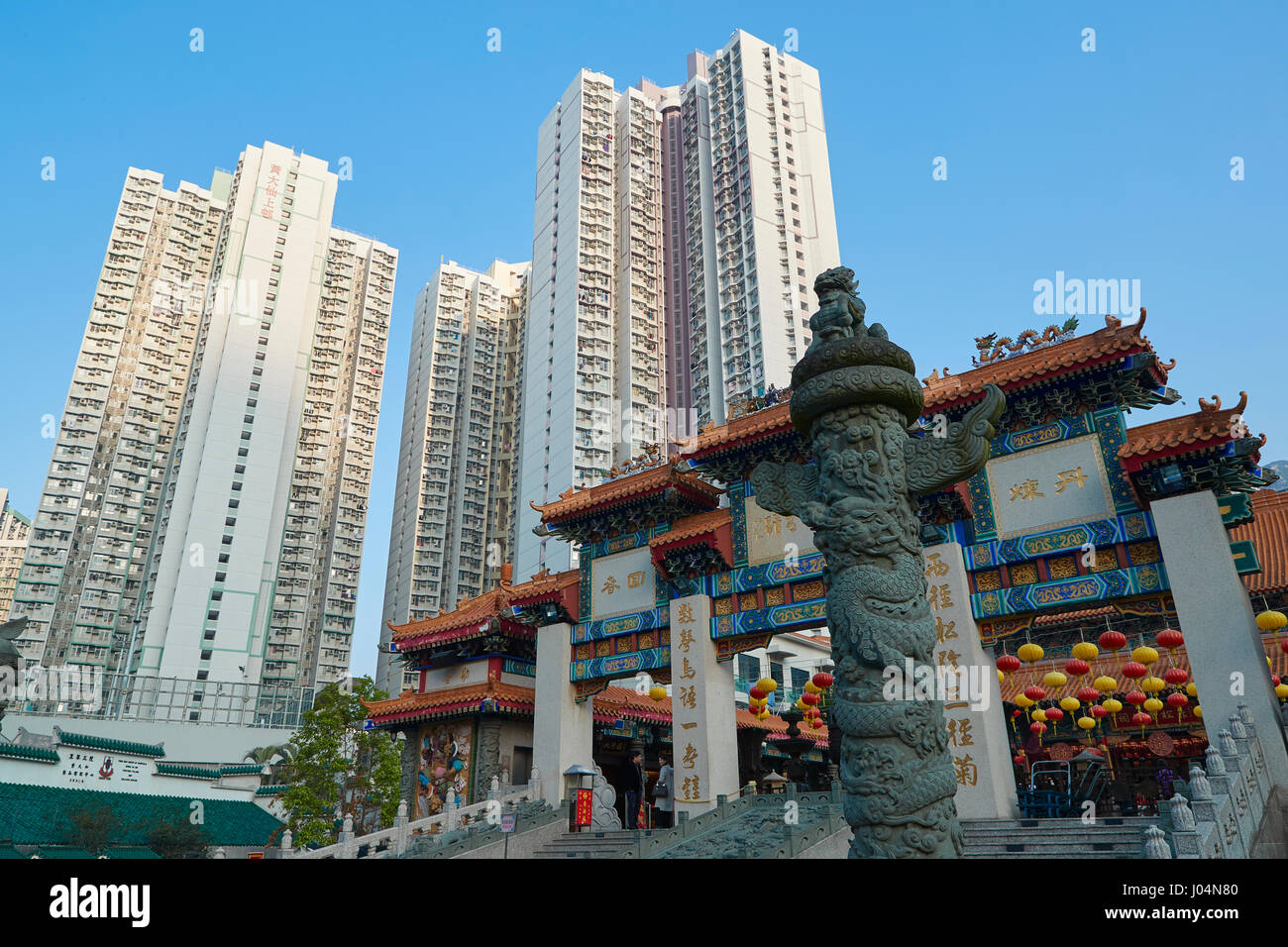 Ornate Traditional Chinese Gateway Contrasts With The Hong Kong Skyline At The Wong Tai Sin Temple, Hong Kong. Stock Photo