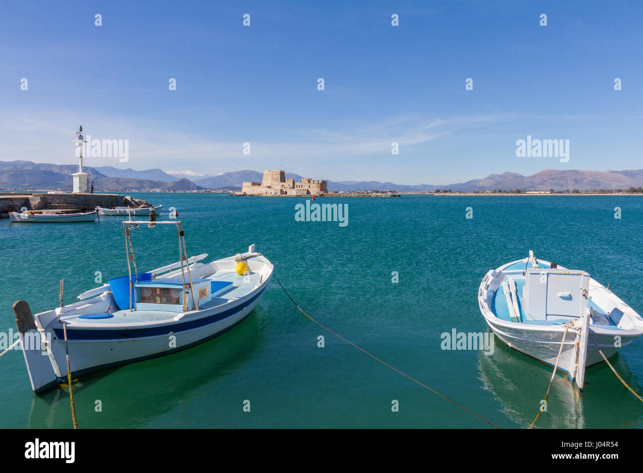 Traditional Wooden Fishing Boats, Lightouse and Bourtzi Fortress in the background in Nafplion, Greece Stock Photo