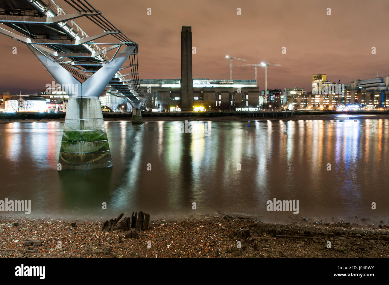 London, England - December 2, 2010: The Millennium Bridge and Tate Modern seen from the banks of the River Thames at night. Stock Photo