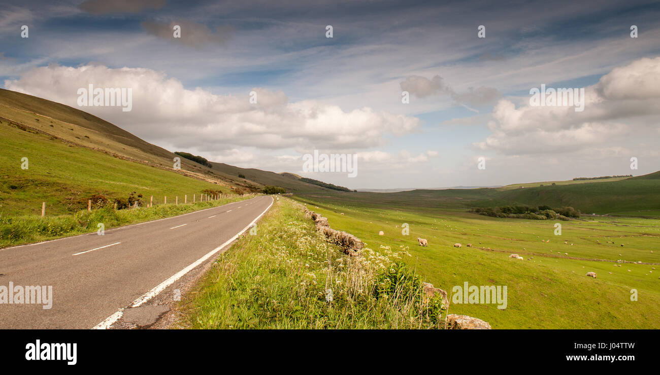 The old Manchester-Sheffield road runs through fields of sheep pastures on the rolling hills of the White Peak District near Castleton in Derbyshire. Stock Photo