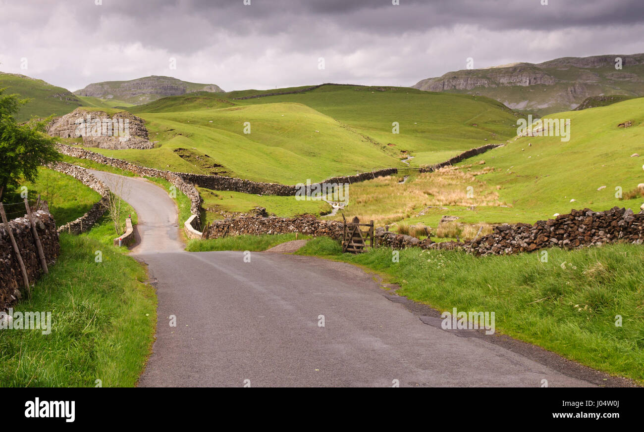 A single track country lane runs through the limestone karst landscape of England's Yorkshire Dales National Park. Stock Photo