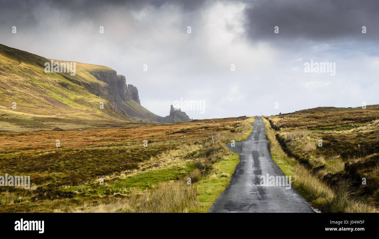 A single track country lane runs through moorland under the Quiraing mountain on Scotland's Isle of Skye. Stock Photo