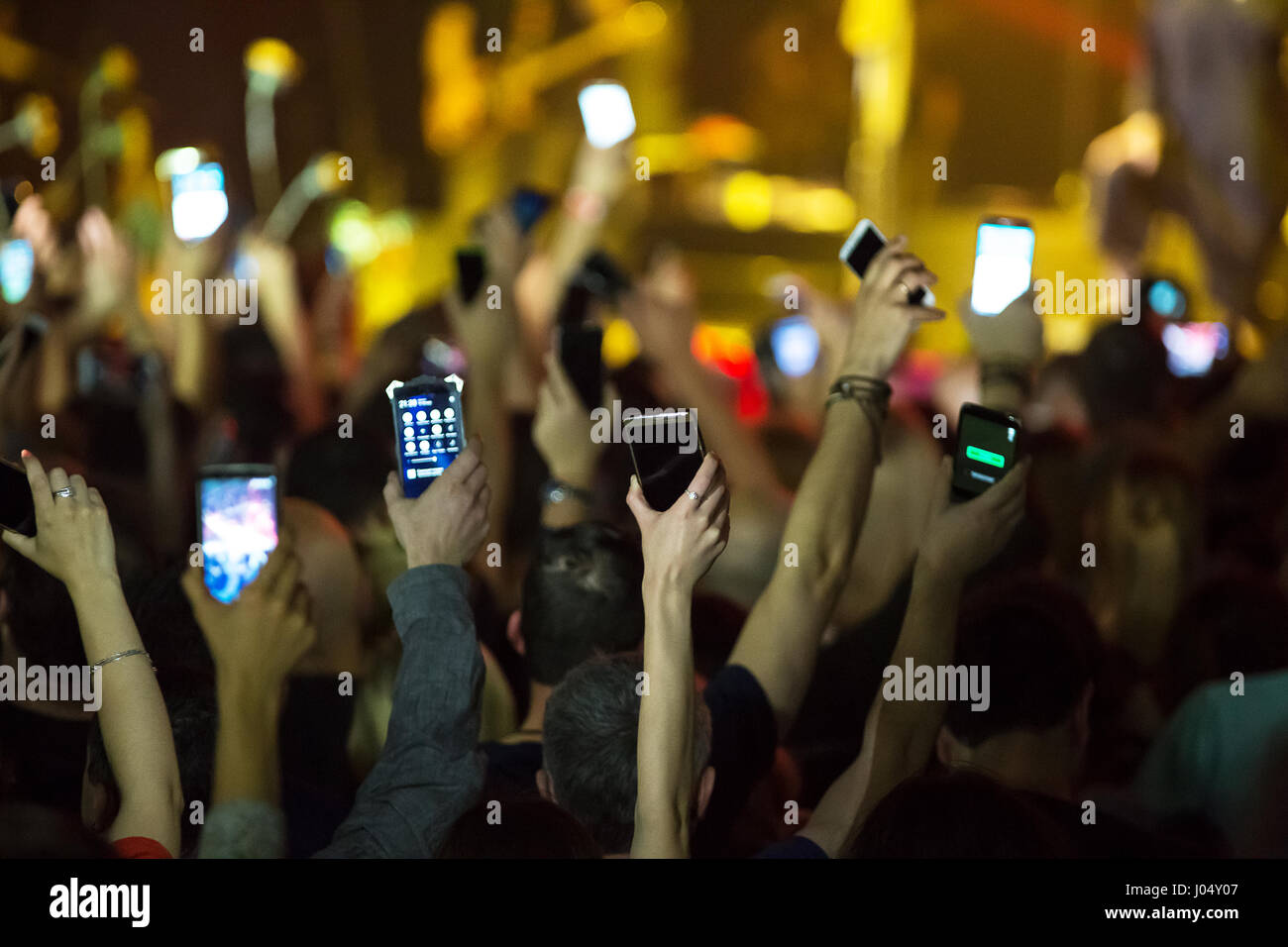 Crowd at concert and blurred stage lights . Close up of photographing with smartphone during a concert . Stock Photo
