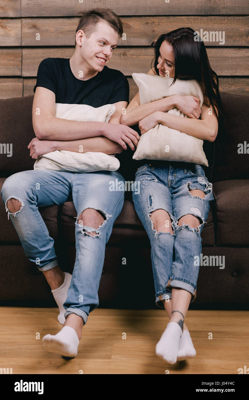 Happy couple in black T shirts and blue jeans look at each other and hug pillows. Concept of a happy family life Stock Photo Alamy