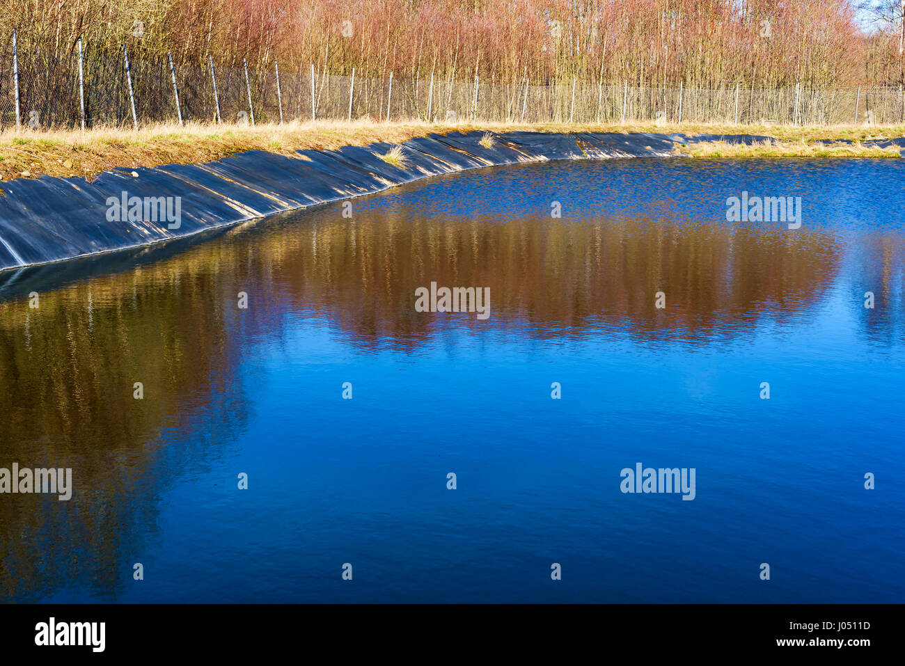 Leachate pond with synthetic lining and surrounding fence. Location Ronneby, Sweden. Stock Photo