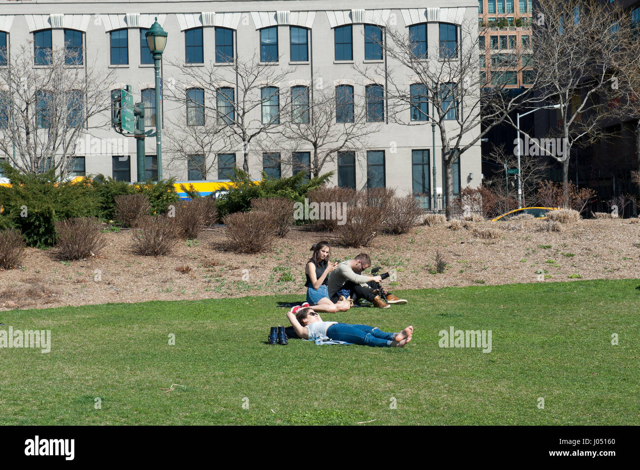 On a sunny day in early spring, people relaxed on a lawn in the Tribeca section of Hudson River Park in Manhattan, New York City. Stock Photo