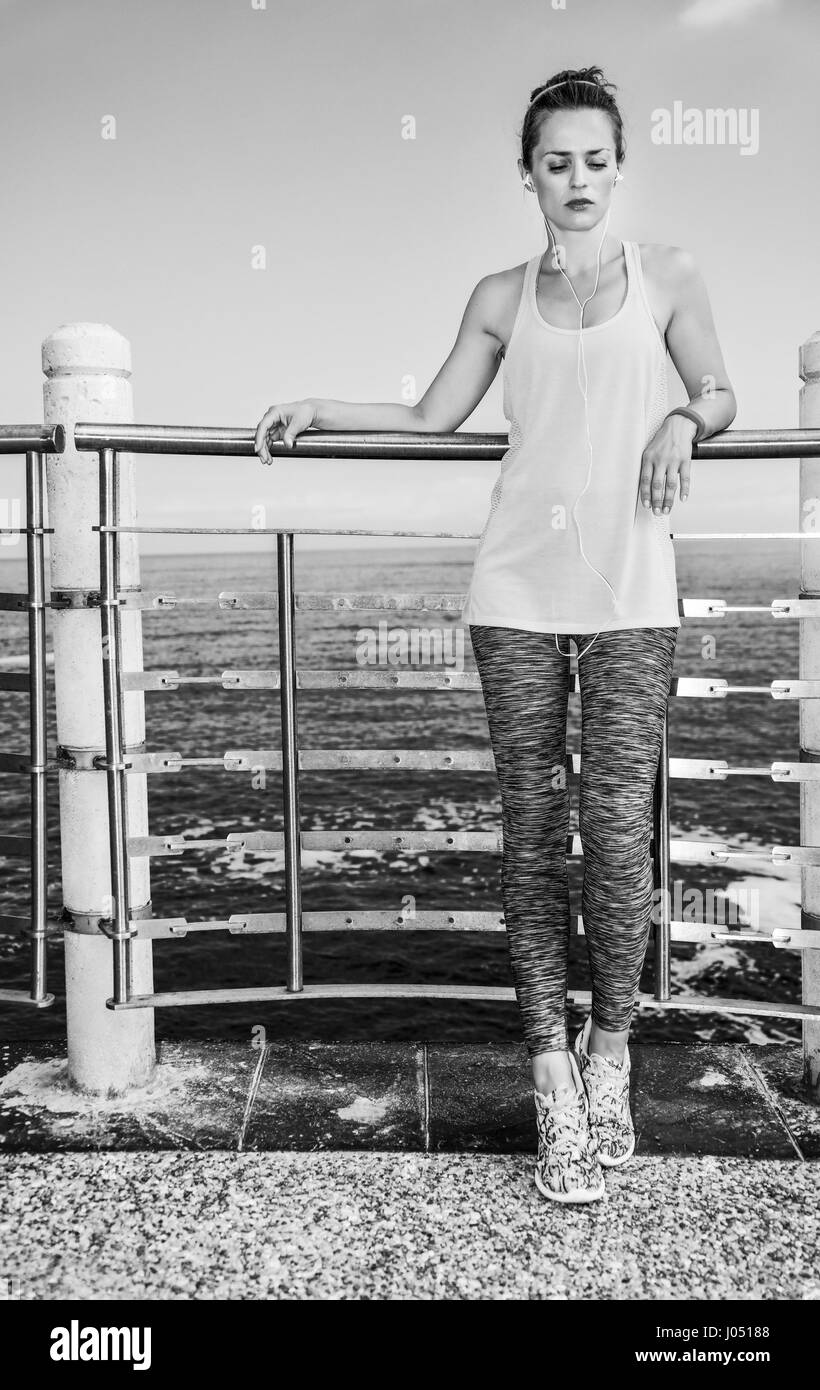 Look Good, Feel great! Full length portrait of young healthy woman in fitness outfit listening to the music at the embankment Stock Photo