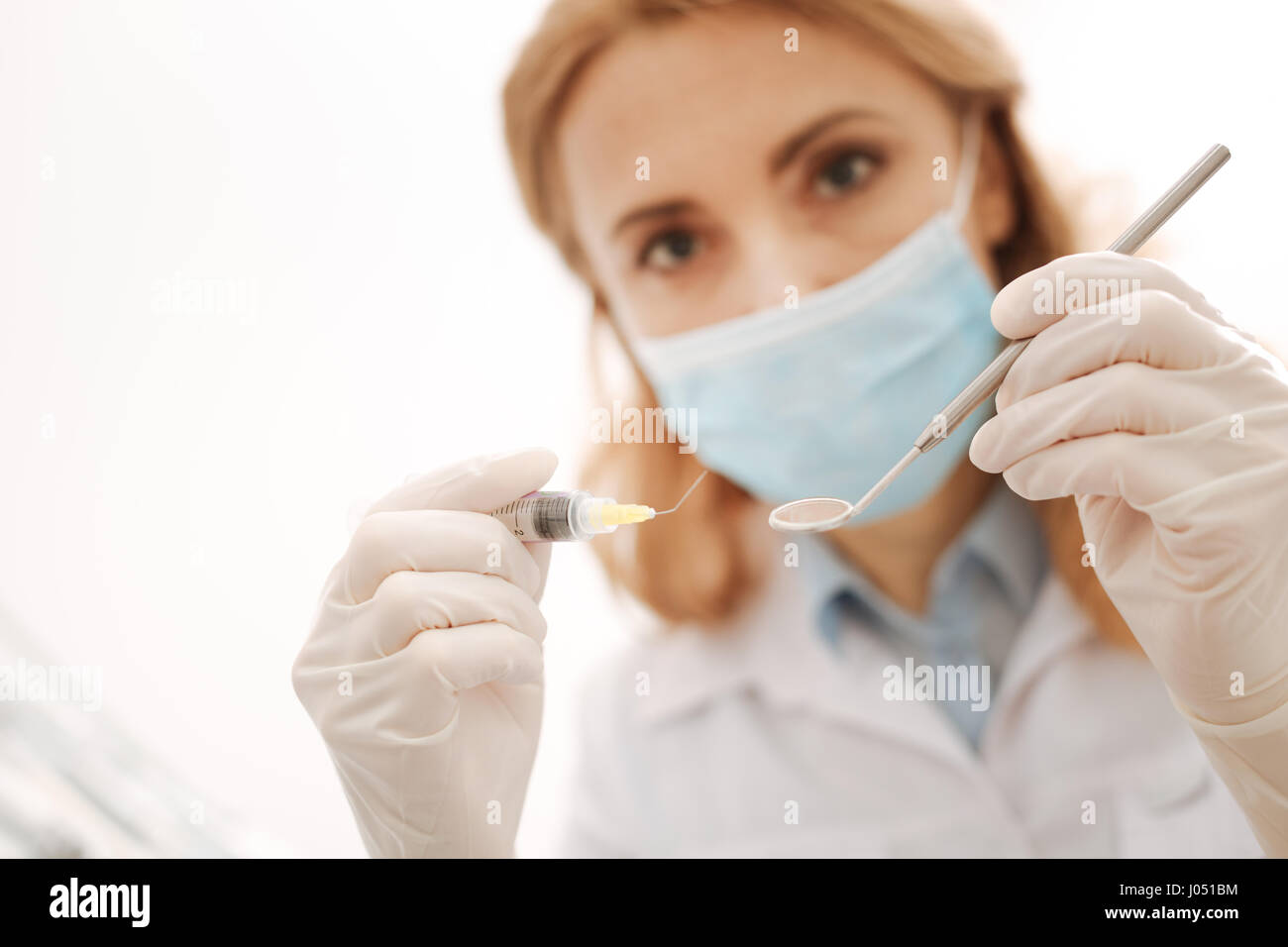 To kill the pain. Wonderful gentle distinguished dentist giving a pain reveling injection while running some procedures using sterile equipment Stock Photo