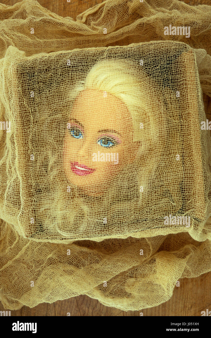 Head of glamorous contemporary doll with blonde hair blue eyes and pink lipstick lying in box covered with gauzy material Stock Photo