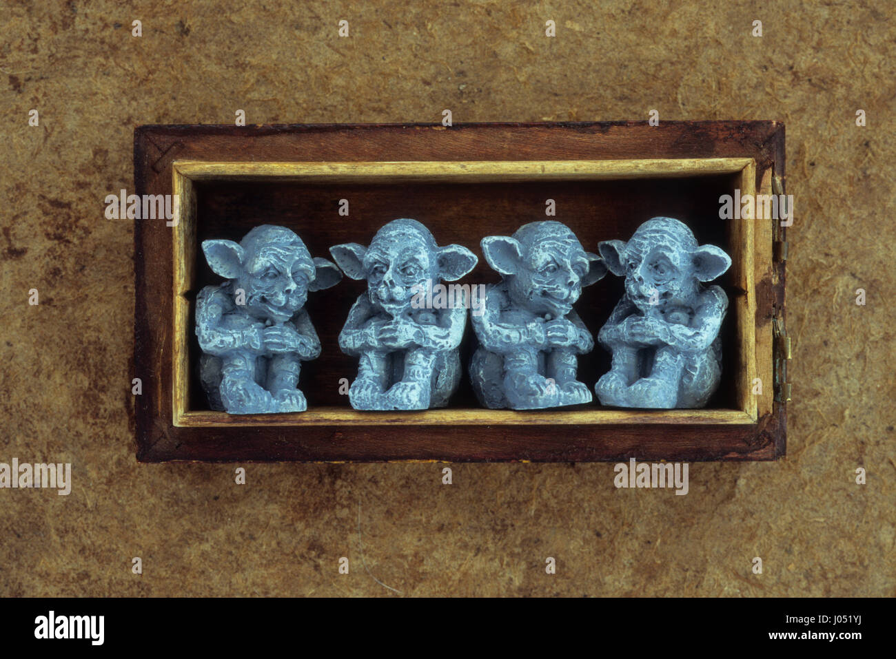 Two pairs of grey seated goblins sitting in conversation in small wooden box Stock Photo