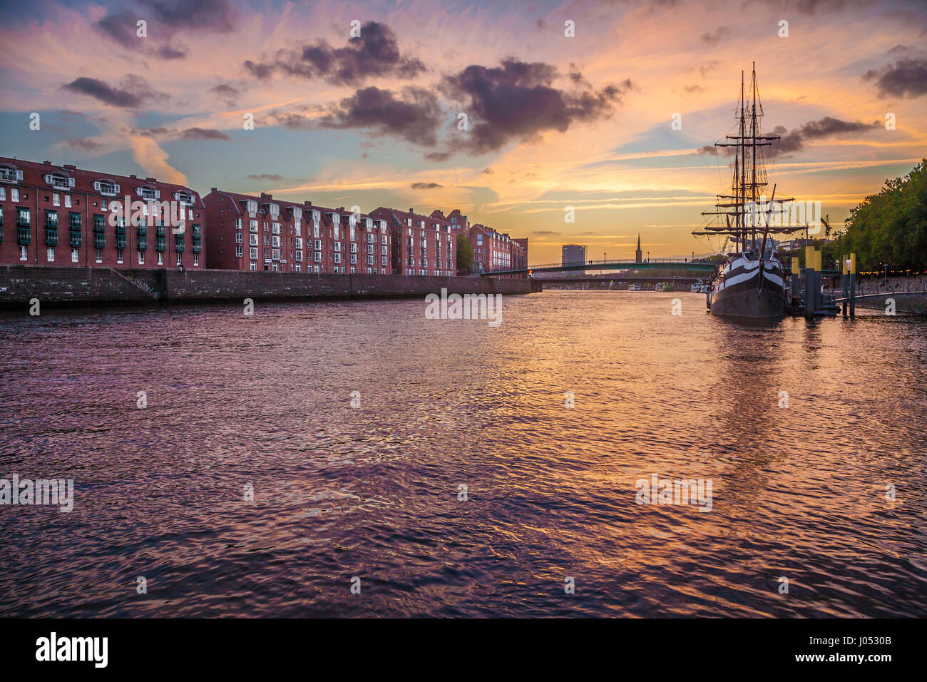 Panorama view of the historic city center of Bremen with an old sail ship on Weser river in beautiful golden evening light at sunset in summer Stock Photo