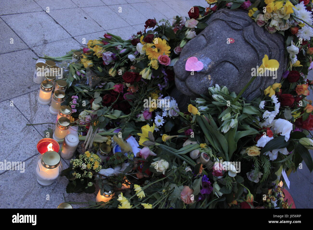 A concrete barricade depicting a lion animal, covered with flowers and burning candles in Drottninggatan street, near Ahlens shopping center, displaying the Swedish sympathy and mourn for the death and casualties of the 7 April 2017, including Iggy the dog, caused by a terrorist truck attacker who mown down innocent pedestrians around Stockholm's city centre. Lions are incorporated into the Swedish Coat of Arms, made by Swedish artist Anders Arfelt and are part part of the Swedish Heraldry. Stock Photo