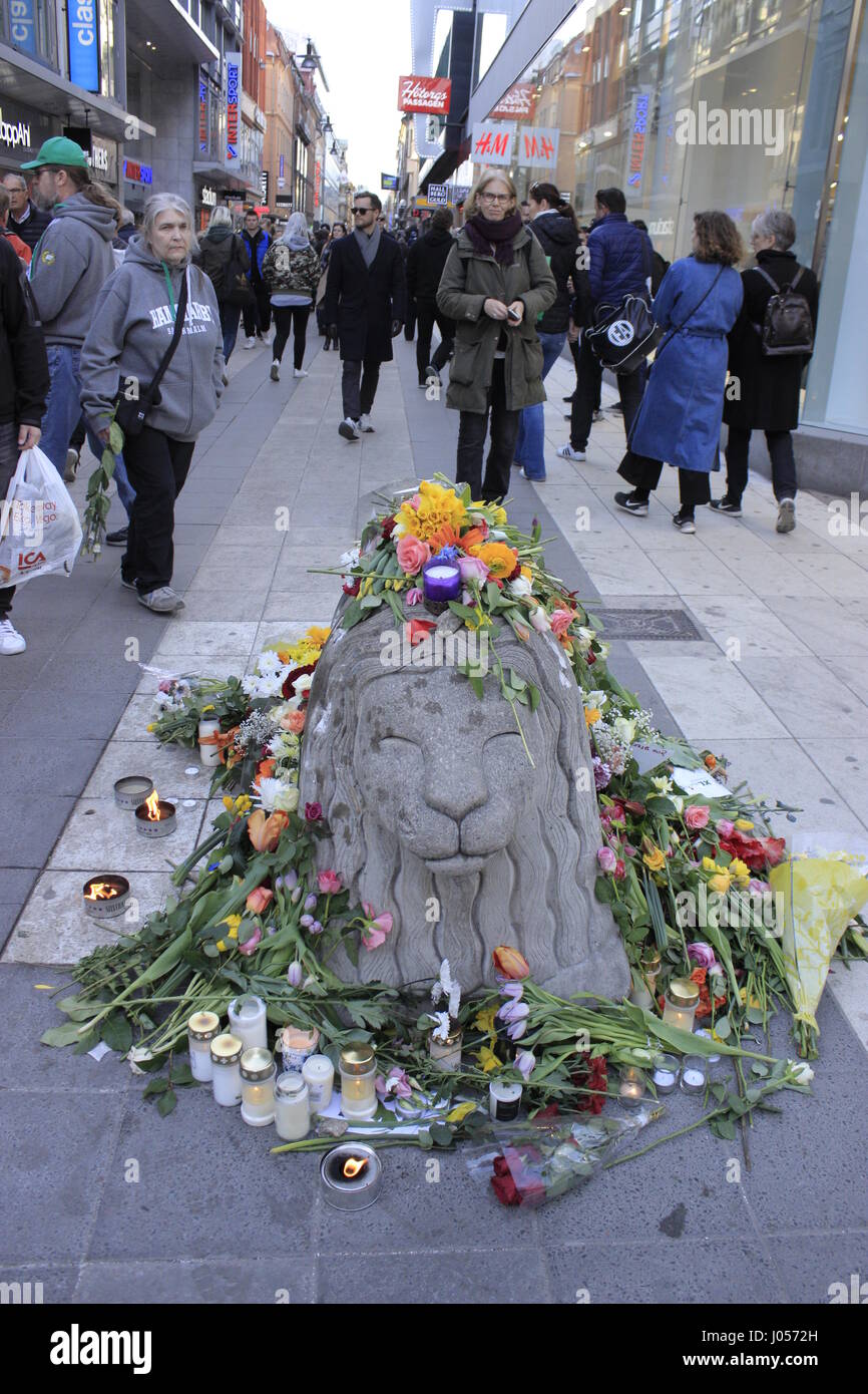 A concrete barricade depicting a lion animal, covered with flowers and burning candles in Drottninggatan street, near Ahlens shopping center, portraying  the Swedish sympathy and mourn for the casualties of the 7 April 2017, caused by a terrorist truck attacker who mown down innocent pedestrians and animals, in Stockholm's city centre. Lions are incorporated into the Swedish Coat of Arms, made by Swedish artist Anders Arfelt and are part part of the Swedish Heraldry. Stock Photo