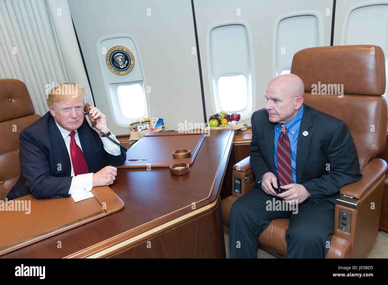 U.S President Donald Trump speaks by telephone with speaks with the commanding officers of the guided-missile destroyers USS Porter and USS Ross from aboard Air Force One as National Security Advisor H.R. McMaster look on April 9, 2017 in flight to Washington, DC. The president thanked the commanders and their personnel for successfully executing the strike against the Shayrat Air Base in Syria. Stock Photo