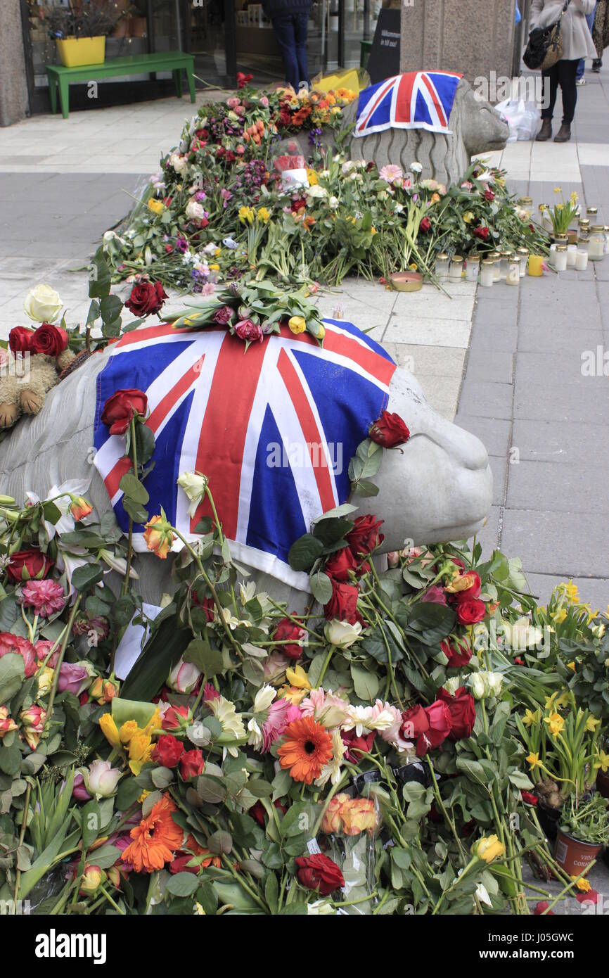 Stockholm, Sweden. 11th April, 2017. British flags & fresh flower bouquets dominate placed on top of the two concrete lion heads at the corner of 78 Drottninggatan & Kungsgatan streets, in respect to the memory of the British citizen and terror victim Chris Bevington. Stockolm city, Sweden. Credit: BasilT/Alamy Live News Stock Photo