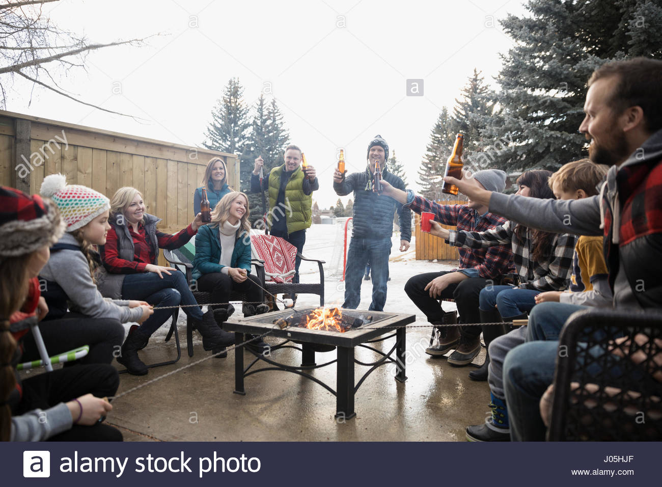 Families, neighbors toasting beer bottles at fire pit in winter