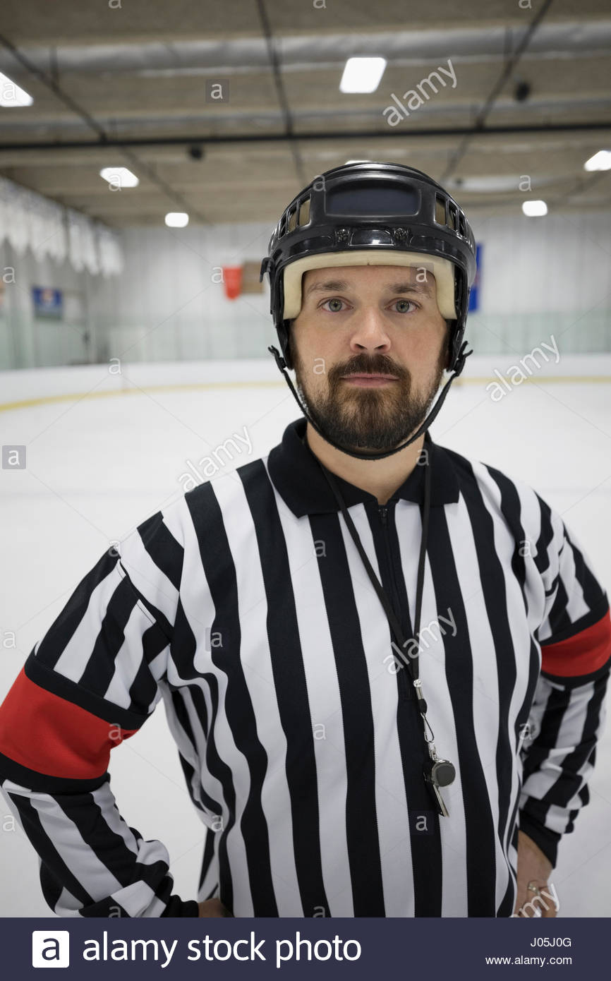 Portrait confident male ice hockey referee with hands on hips on ice