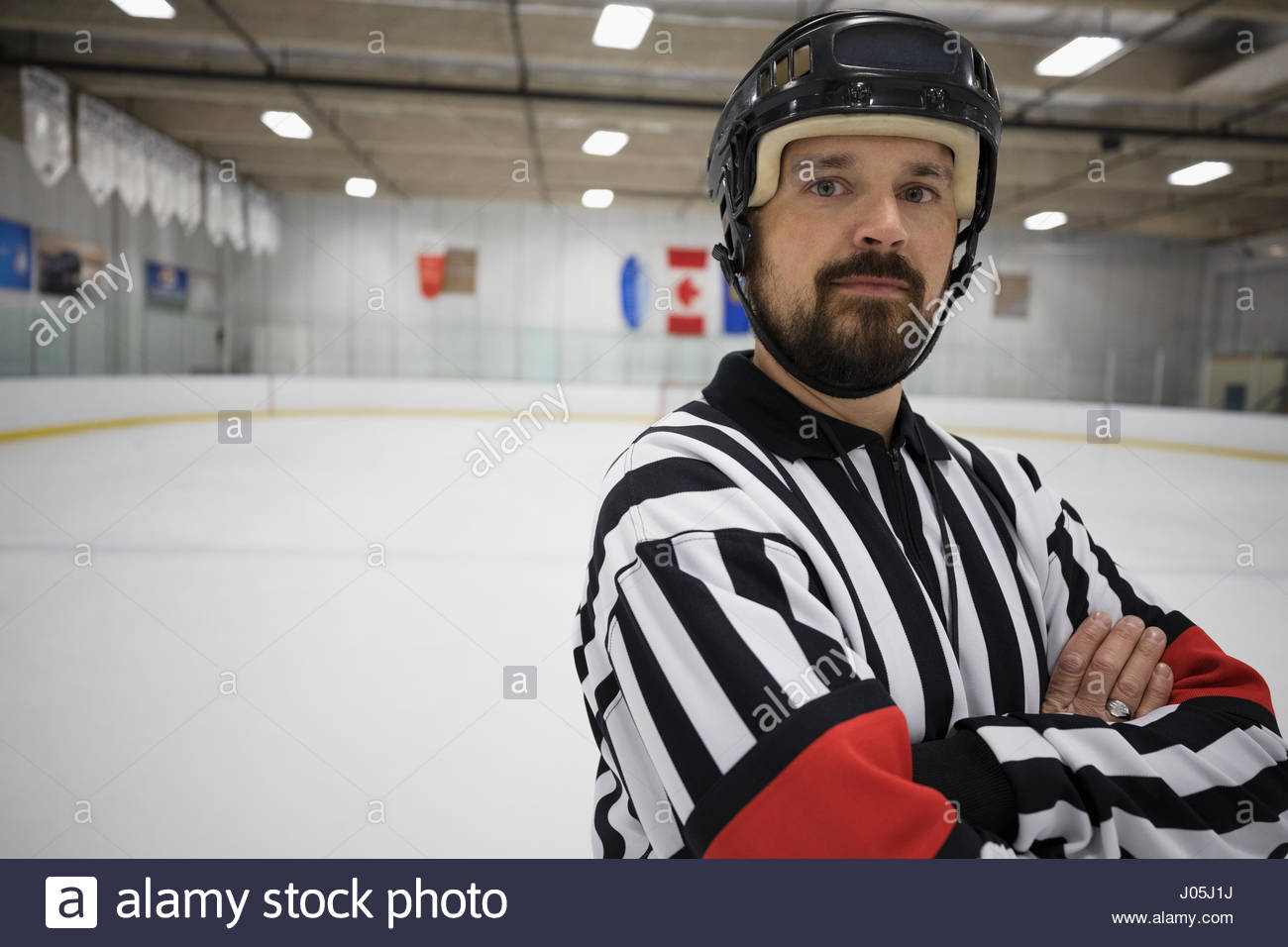 Portrait confident male ice hockey referee with arms crossed on ice