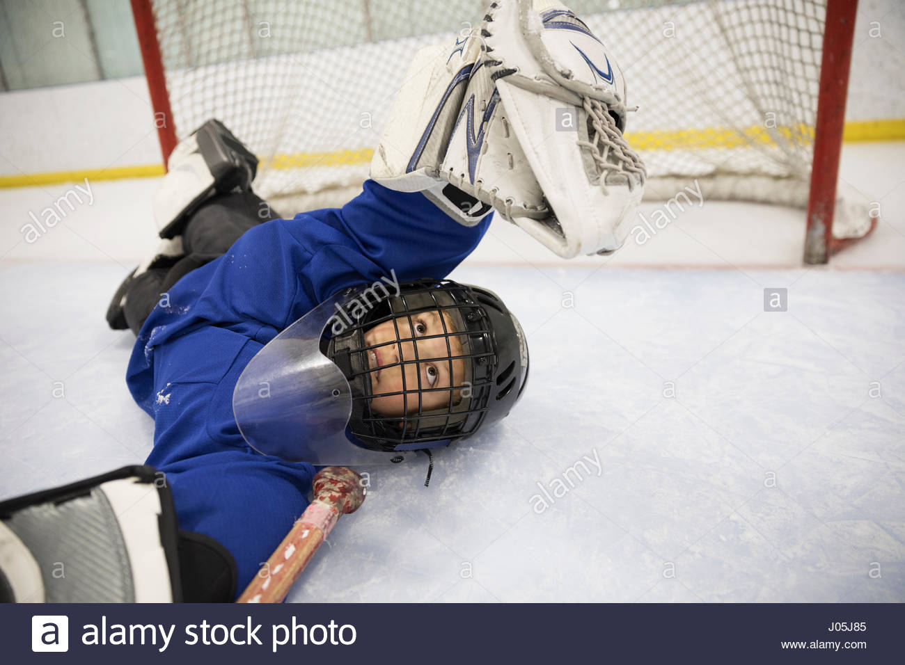 Boy ice hockey player goalie grabbing puck at net on ice Stock Photo