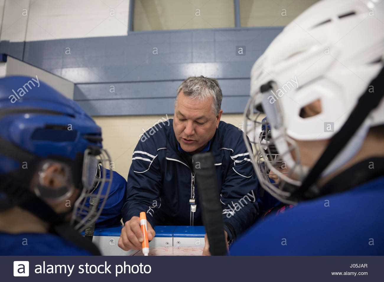 Ice hockey coach reviewing game plan with boy hockey players at