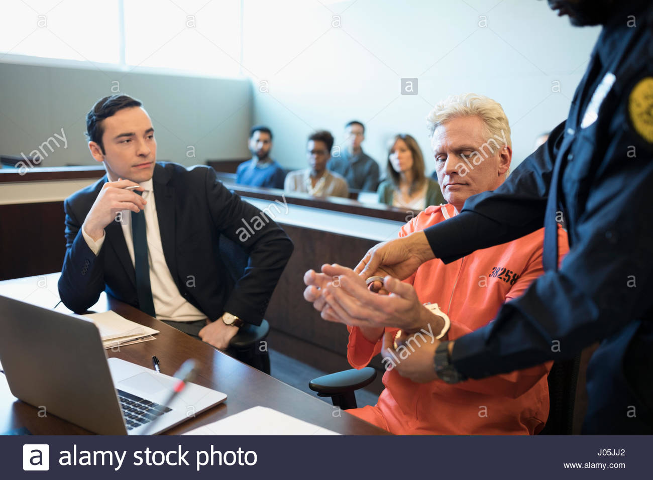 Bailiff handcuffing defendant criminal at table in legal trial courtroom Stock Photo Alamy