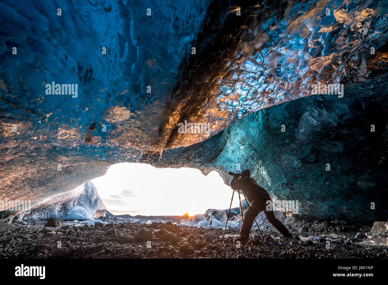 ICELAND: THESE cold-as-ice explorers were-willing-to-sacrifice in order to capture these magnificent ice caves before they melt away. Stunning images have revealed ice-cool British tourists chilling out inside Europe’s largest glacier – despite being at risk of flooding. The spectacular collection of images show the explorers braving the freezing temperatures to climb, photograph and even abseil down the inside of the icy cliff sides.  Another image shows one visitor on his knees appearing to pray next to a water fall of melted ice.  Other glistening shots show an adventurer trying to keep war Stock Photo