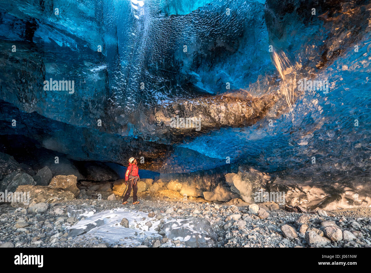 ICELAND: THESE cold-as-ice explorers were-willing-to-sacrifice in order to capture these magnificent ice caves before they melt away. Stunning images have revealed ice-cool British tourists chilling out inside Europe’s largest glacier – despite being at risk of flooding. The spectacular collection of images show the explorers braving the freezing temperatures to climb, photograph and even abseil down the inside of the icy cliff sides.  Another image shows one visitor on his knees appearing to pray next to a water fall of melted ice.  Other glistening shots show an adventurer trying to keep war Stock Photo