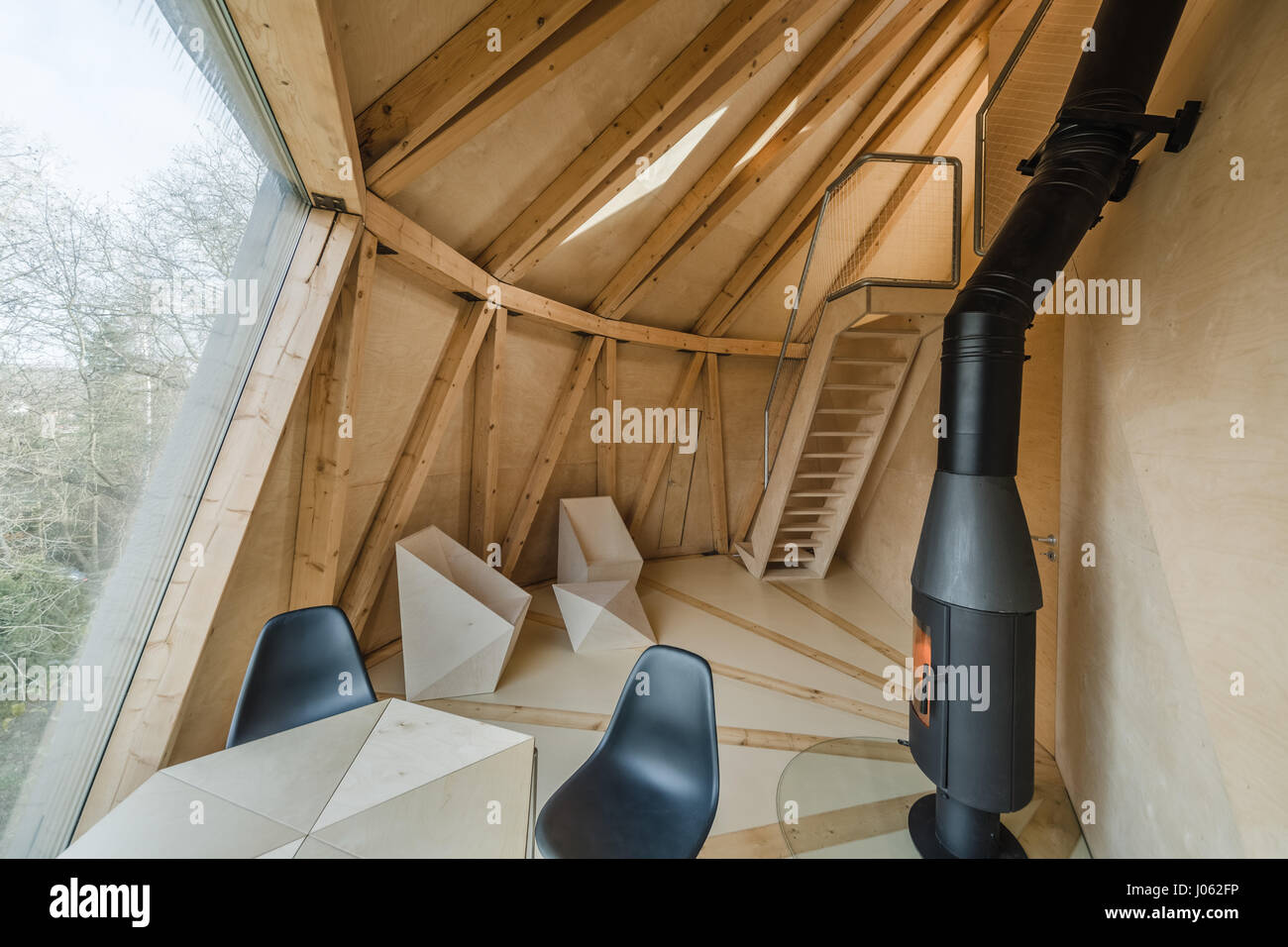 CZECH REPUBLIC: The living room. LIKE A house from a children’s fairy tale this quirky home set in a stunning orchard looks just like a giant pear. The series of quirky images show inside the home’s curved interior of the living room complete with cosy wood burner and narrow kitchen and bathroom. One shot even shows a floor length window open towards the outdoors. Exterior shots show the pear-shaped home’s concrete foot that supports its structure and another photo shows a steel footbridge that connects to the ground below. The home also known as the House in the Orchard is built on a slope an Stock Photo