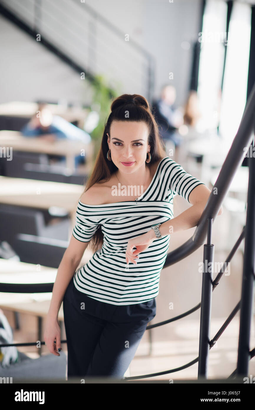 Portrait Of Beautiful Young Woman Standing In A Cafe Leaning On