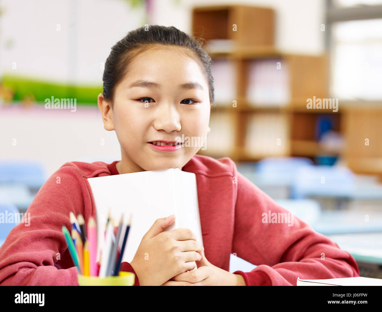portrait of an asian elementary schoolgirl looking at camera smiling. Stock Photo