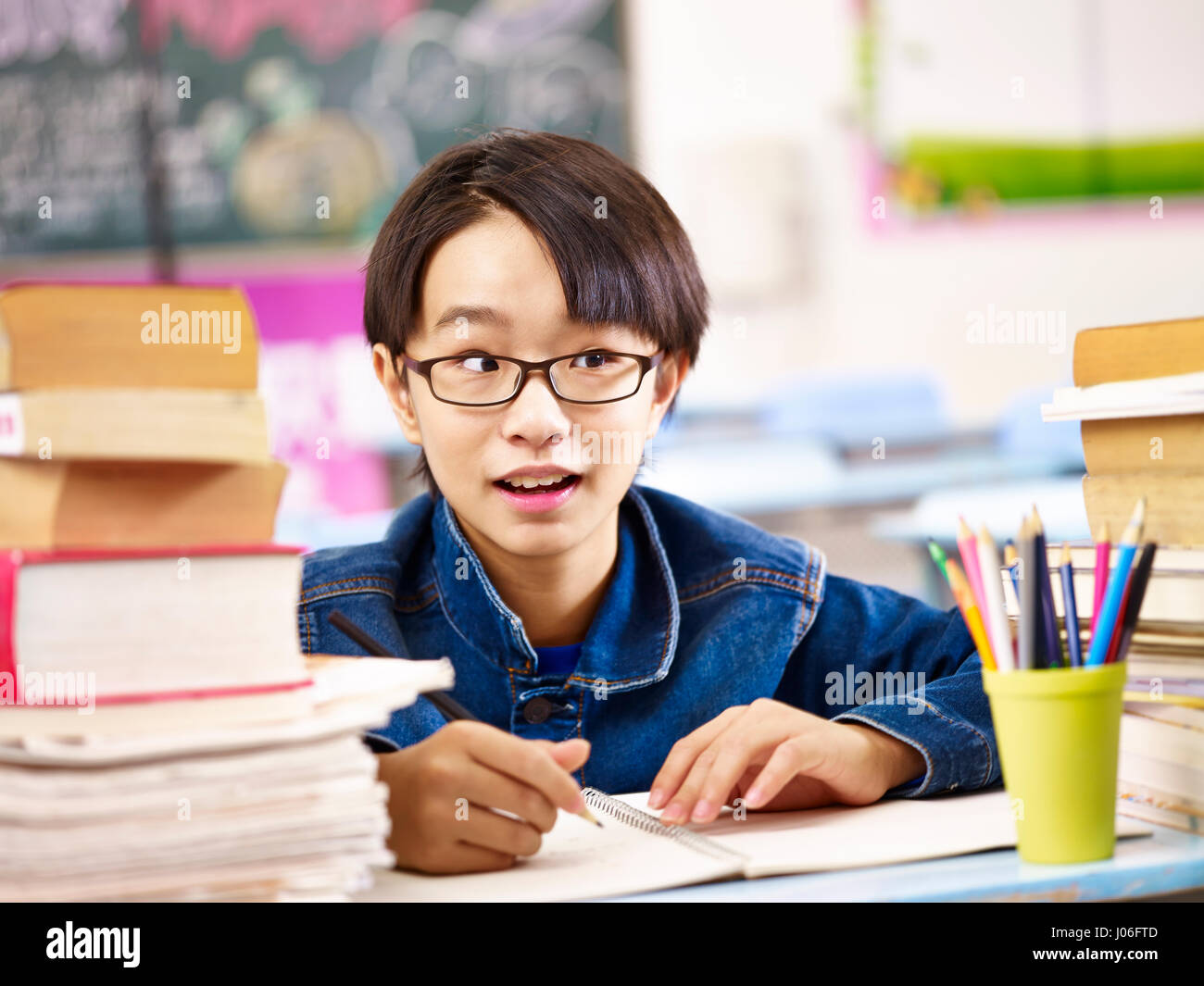 asian elementary schoolboy with funny and cute facial expression studying in classroom. Stock Photo