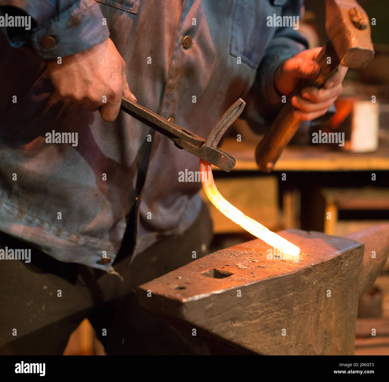 Making of horseshoe. Male worker with pliers and hammer making