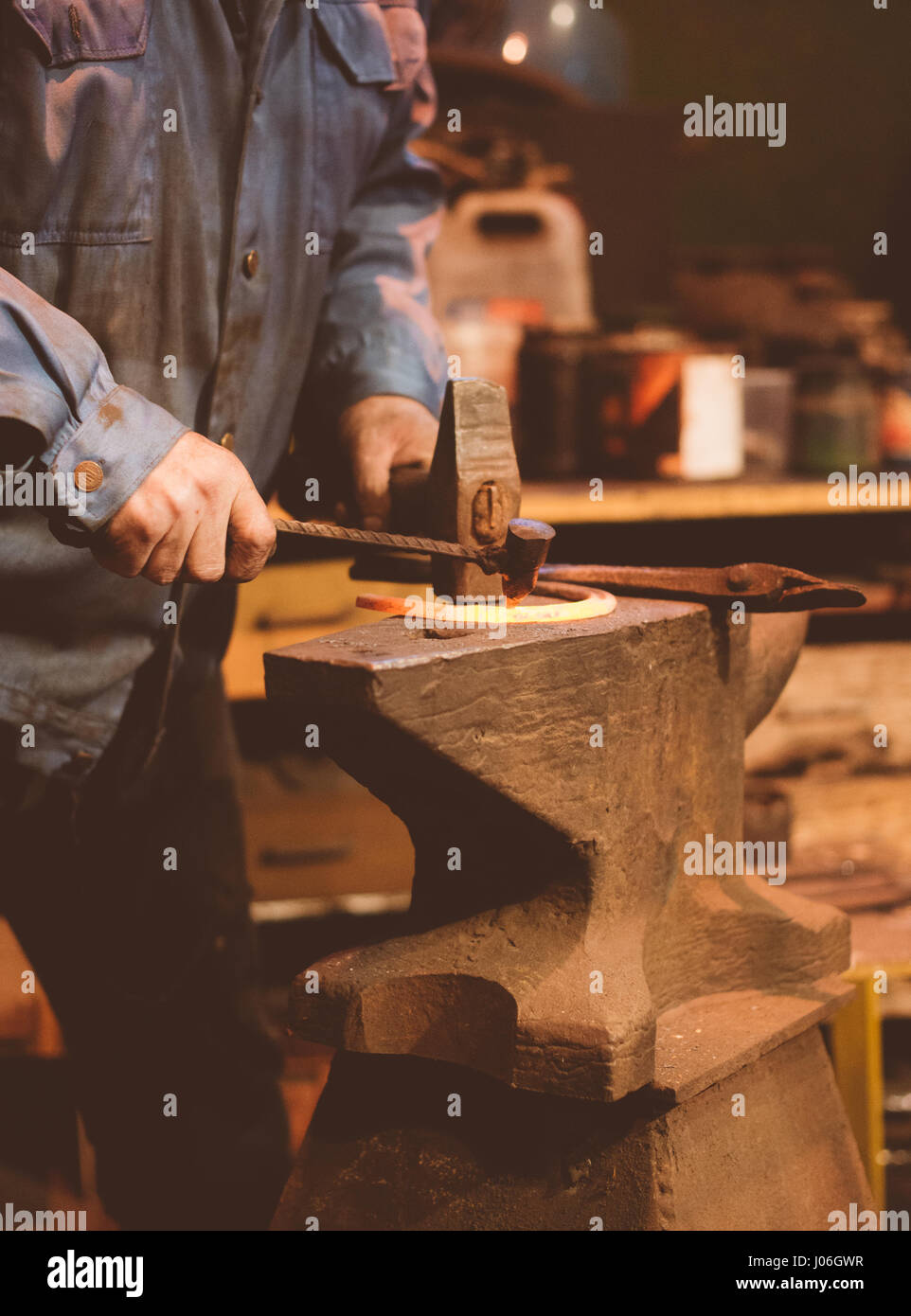 Making of horseshoe. Male worker with hammer making nail holes on