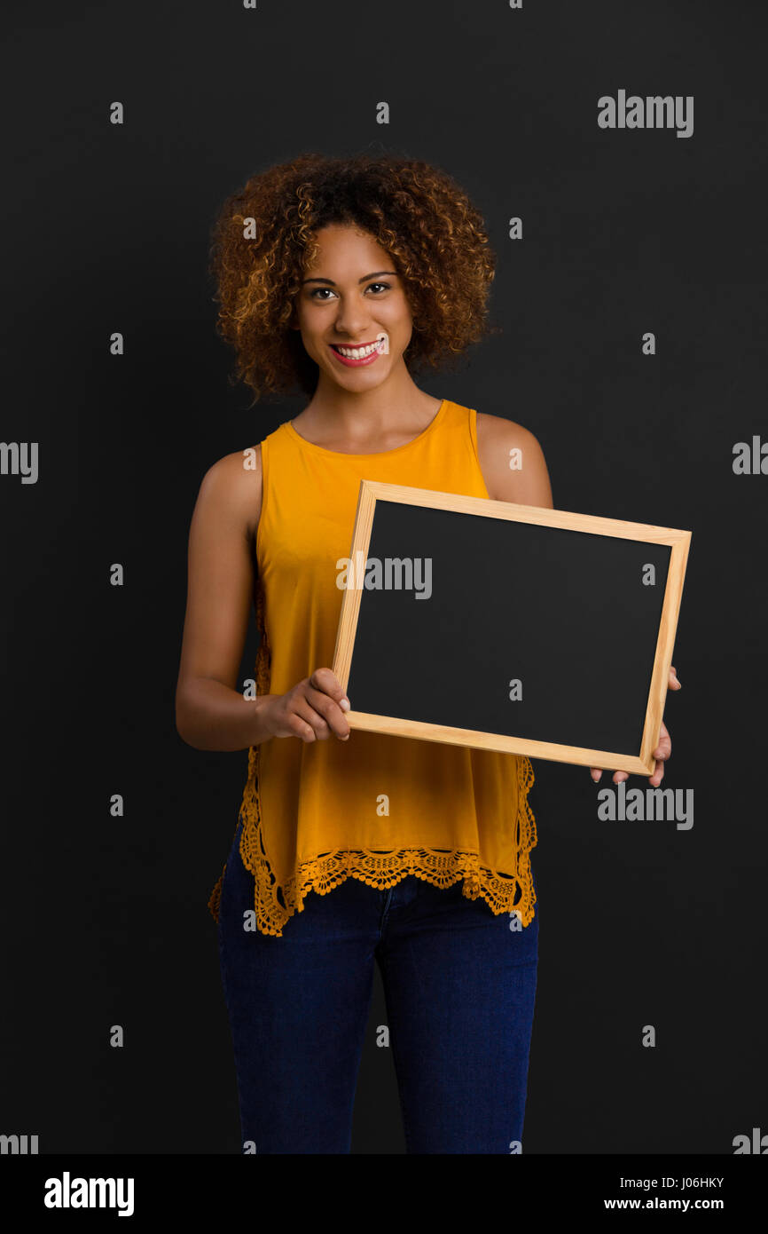 Beautiful African American woman showing something on a chalkboard Stock Photo