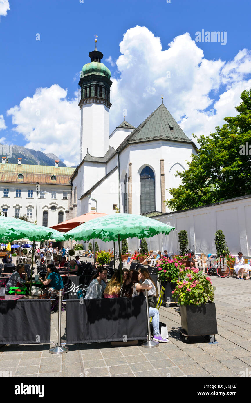 People eating and drinking under large umbrelas in the square by the