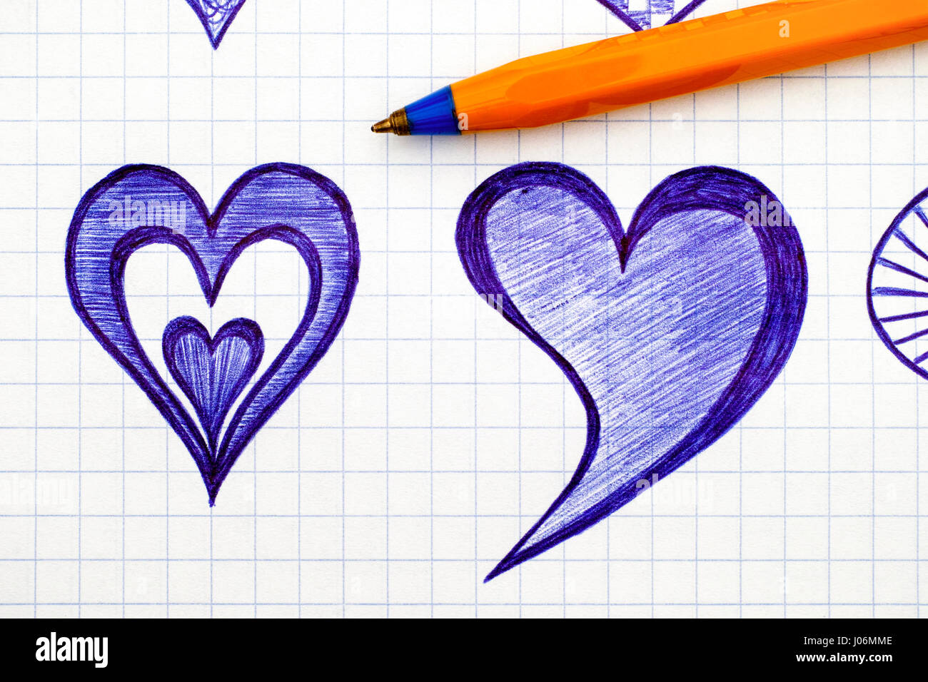 Close-up of hand drawn hearts on the sheet of checkered paper with ballpoint pen. Doodle style. Stock Photo