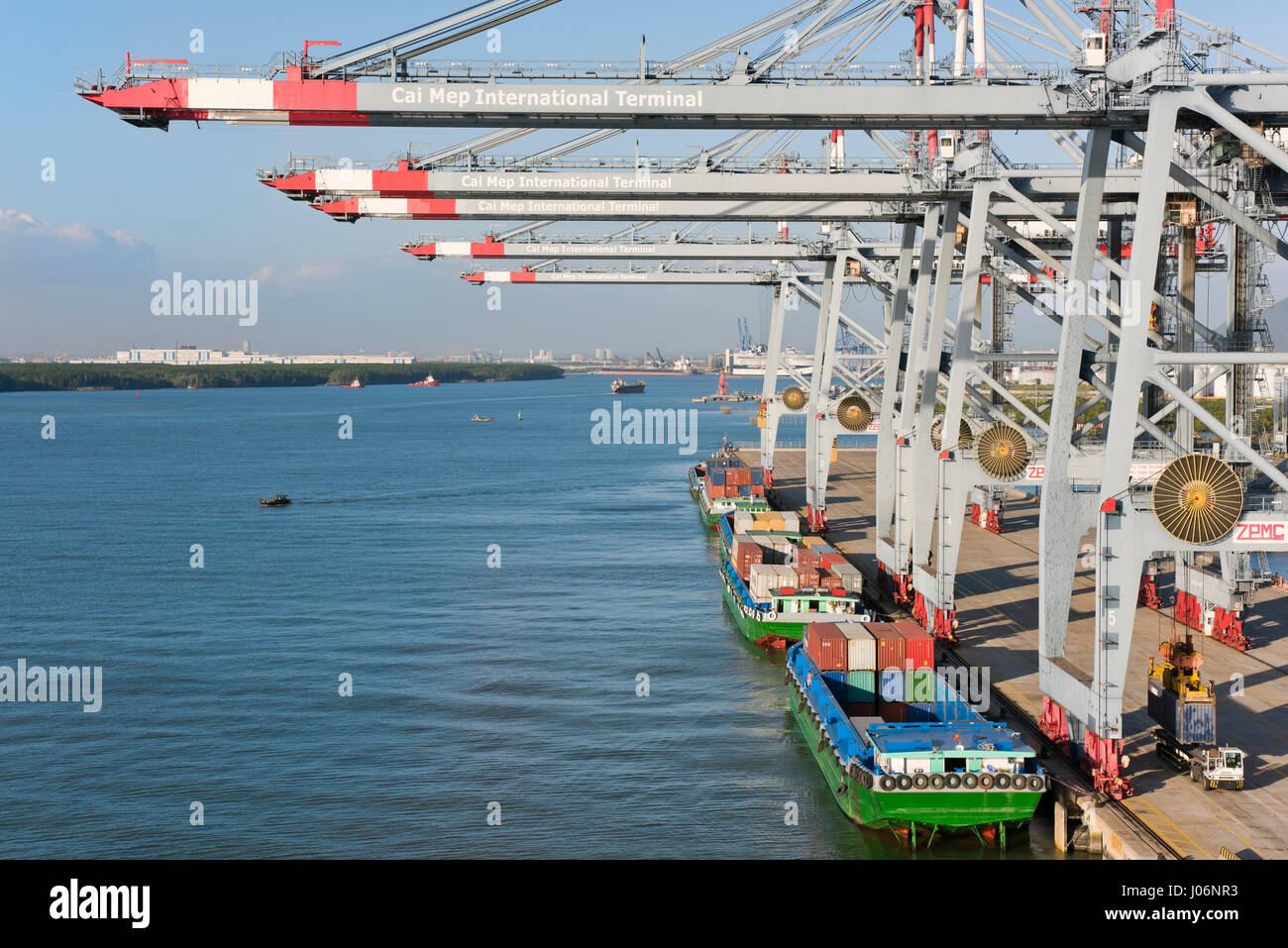 Horizontal view of cranes loading and unloading container ships at a deep water port in Vietnam. Stock Photo
