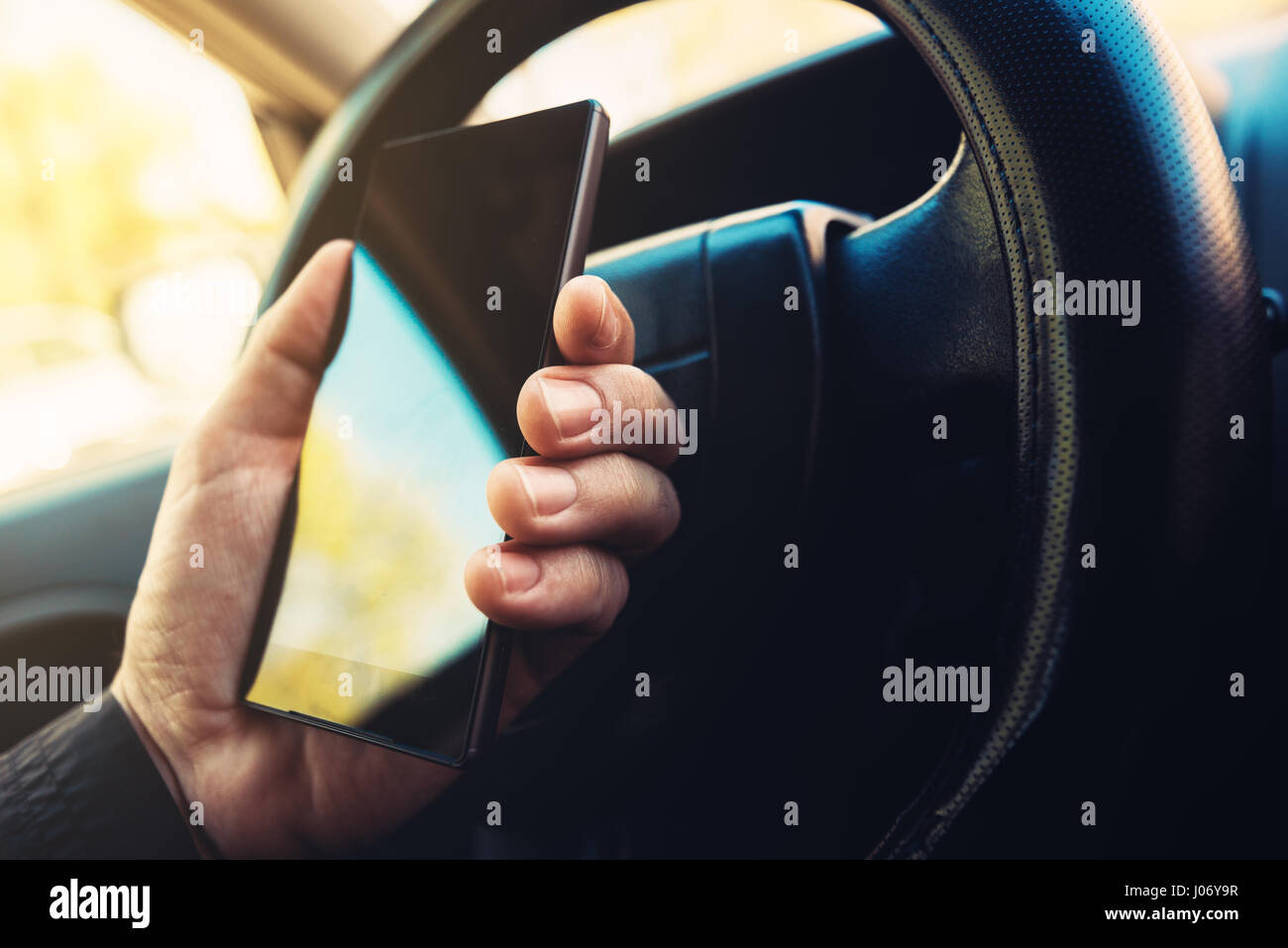 Using mobile phone and driving car, smart phone in male hand on