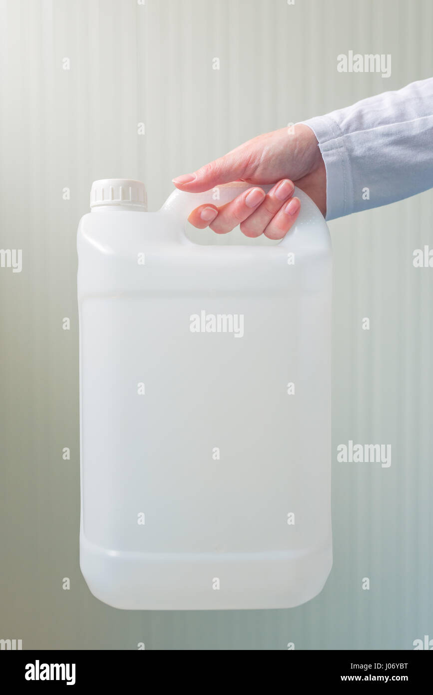 White unlabeled plastic 5 liters tank canister in female hand, chemistry and chemical liquids mock-up container Stock Photo