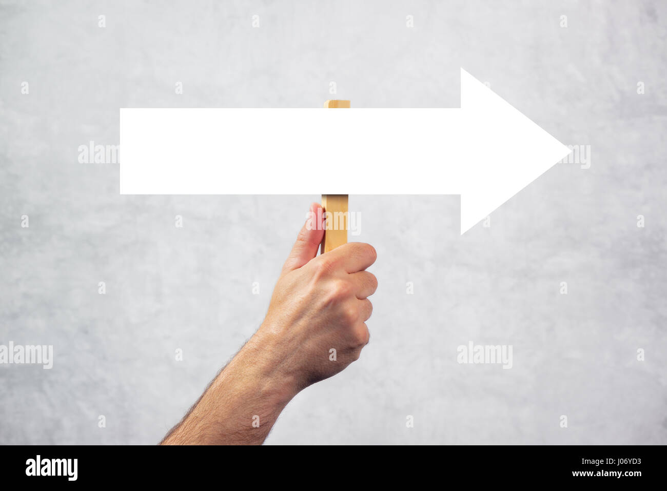 Man holding guiding direction arrow sign in hand, concept of guidance and decision making Stock Photo
