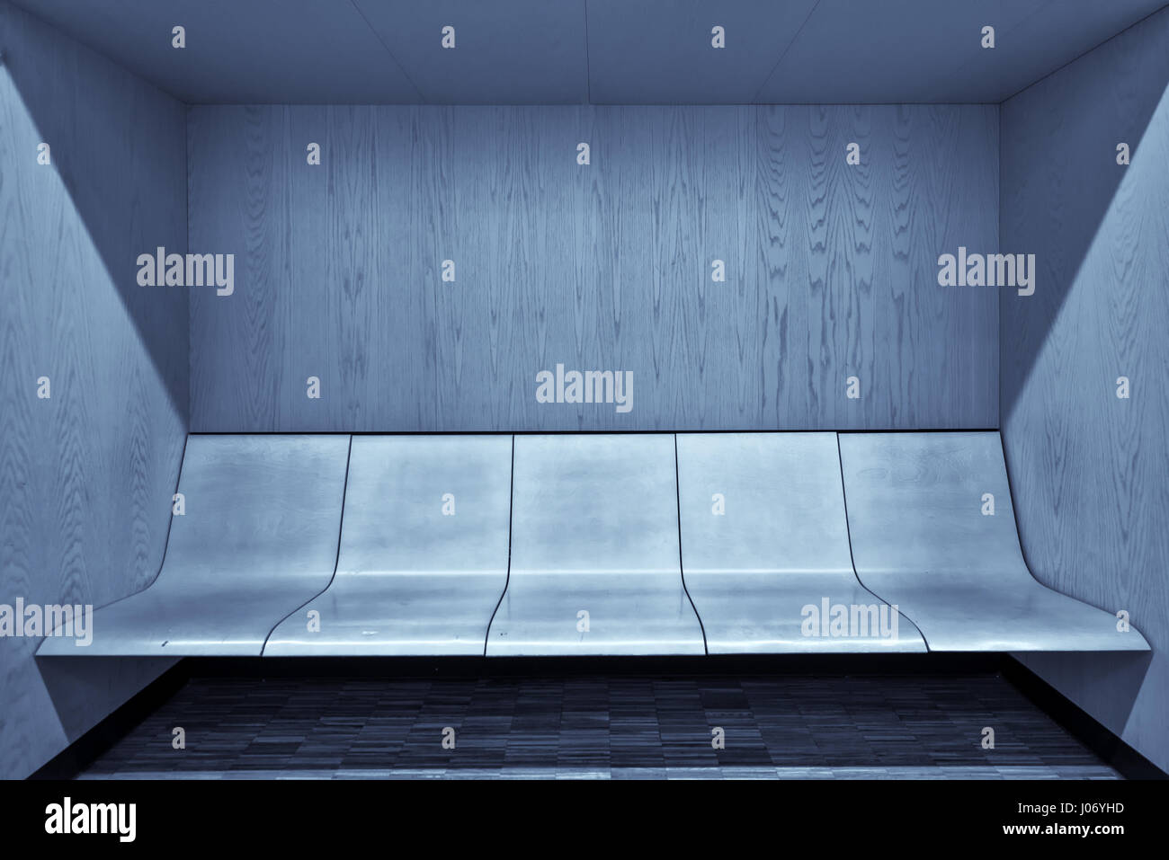 Modern waiting room interior with empty wooden seats and hardwood flooring Stock Photo