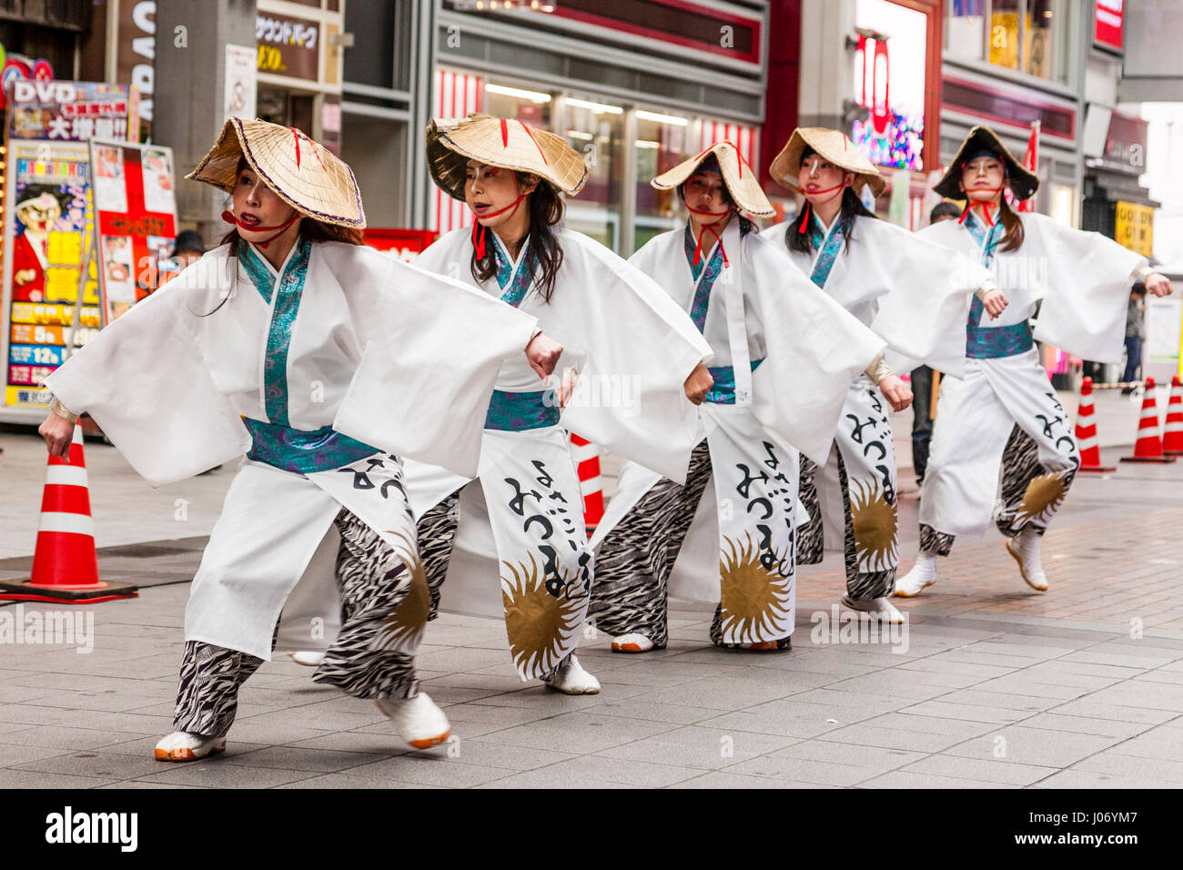 Hinokuni Yosakoi dance festival. Line of five women dancers in farmer costume, white yukata, with straw hats, dancing in shopping mall. Stock Photo