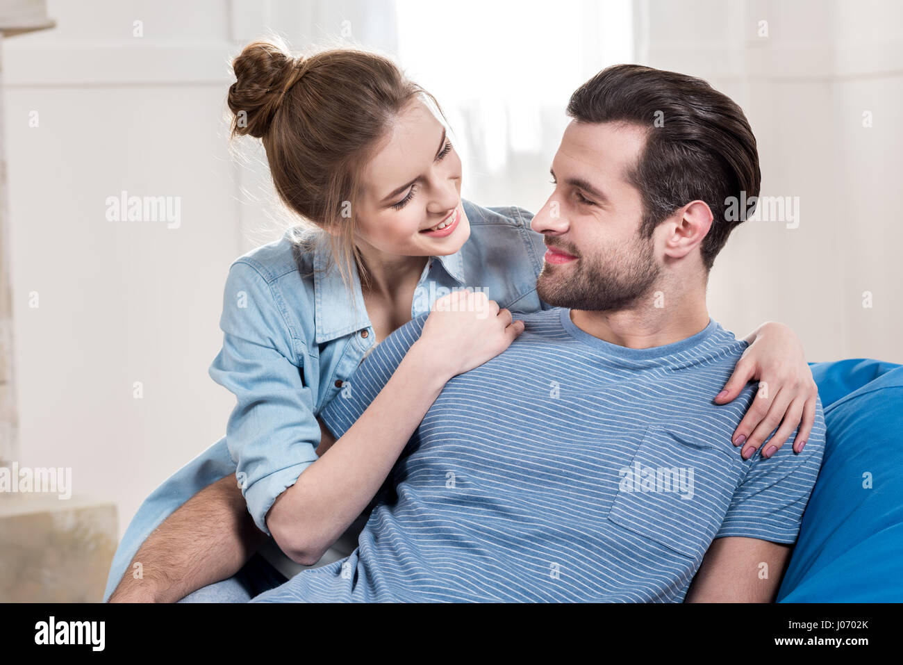 Portrait of happy young couple hugging and looking at each other at ...