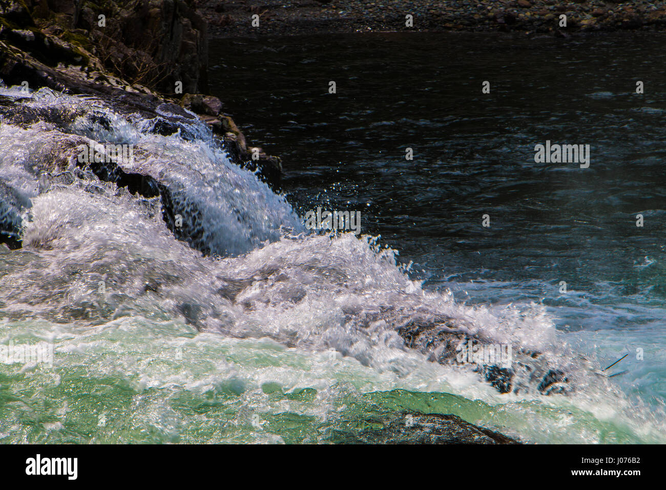A freeze frame of water splashing over a slight fall in the river. Stock Photo
